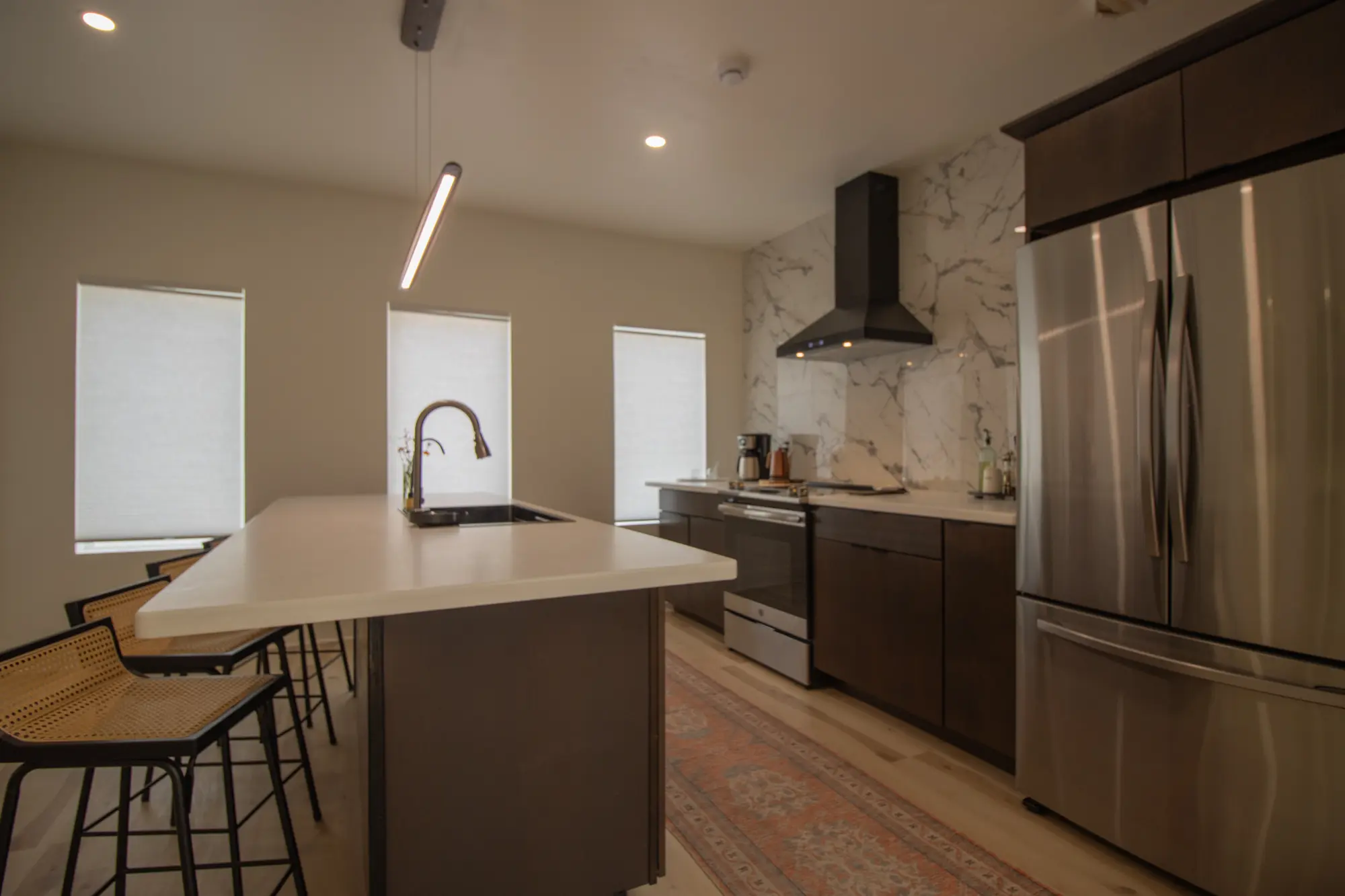 River Penthouse kitchen with marble backsplash, hood vent, stainless appliances, and bar seating, Narrowsburg NY